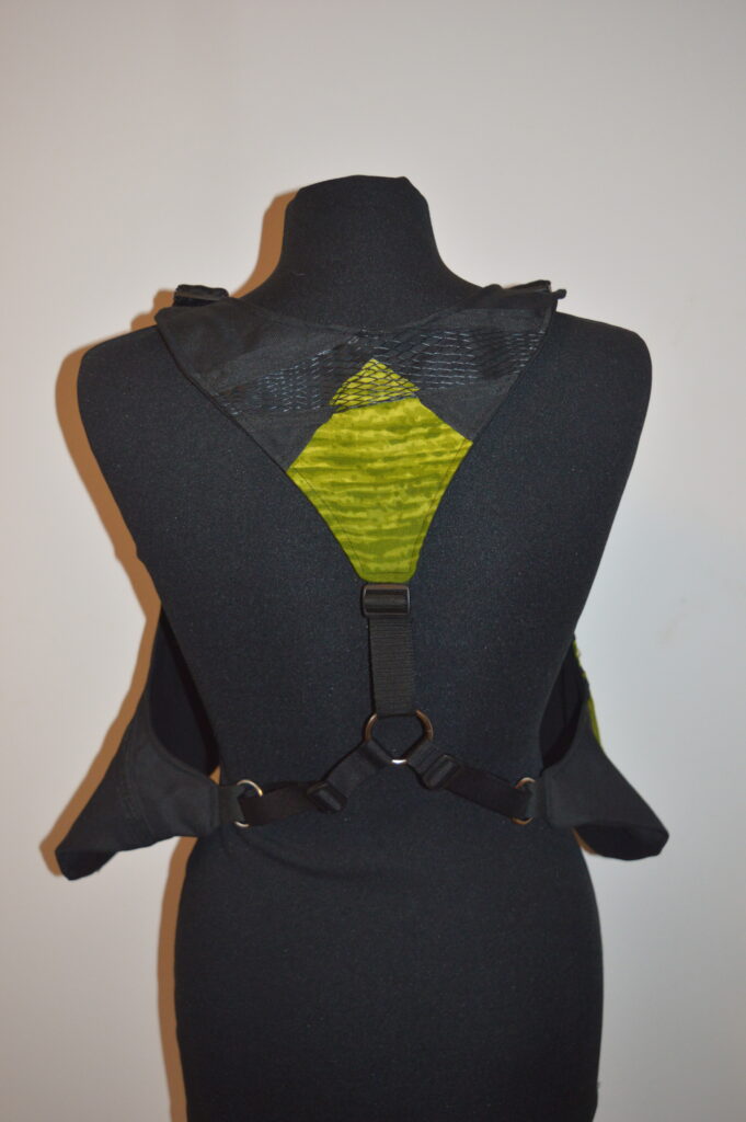 Back view of a black and green garment displayed on a mannequin, featuring straps and a unique design.